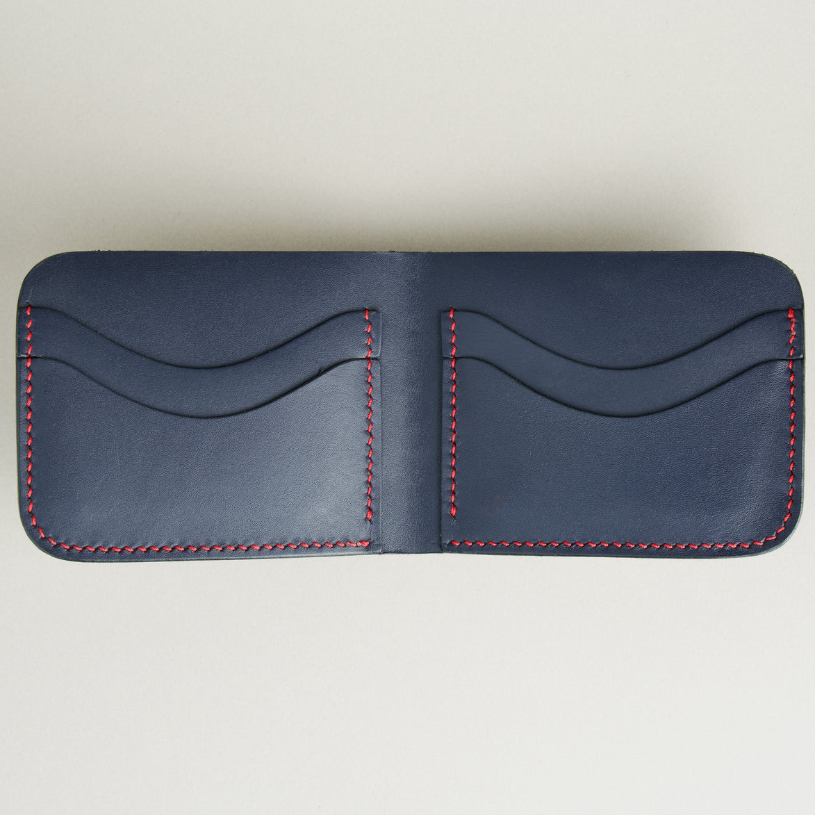 Inside view of full-grain leather bifold wallet with card slots and hand-stitched red thread in Dark Blue. Markore Hunza Arc.
