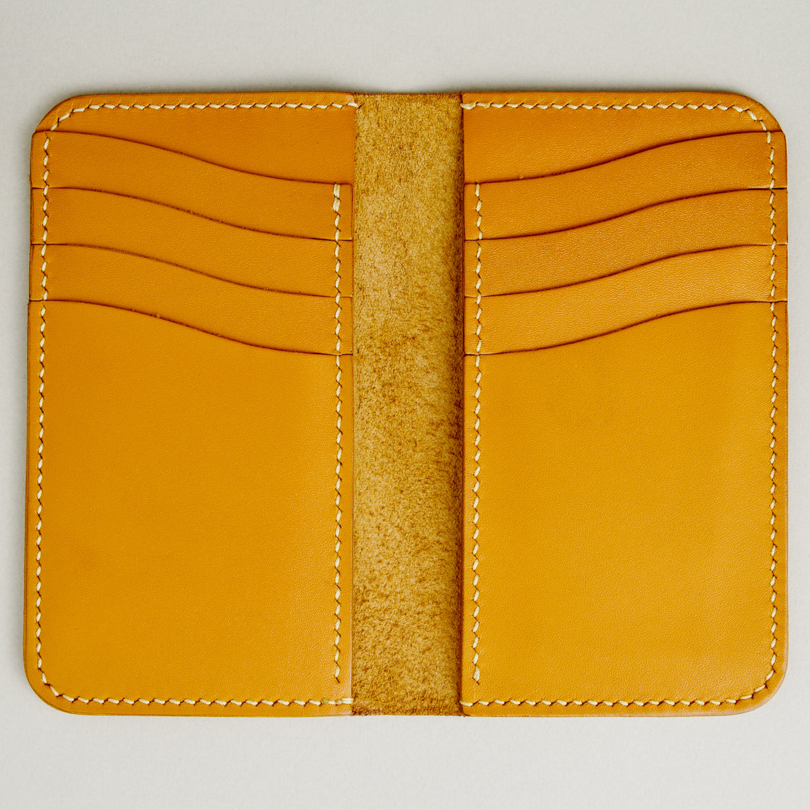 Inside view of vertical full-grain leather bifold wallet in amber, with cards lots and handmade stitching. Markore Karakoram II.