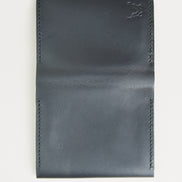 Outside view of midnight black full-grain leather flap fold wallet featuring handmade stitching and embossed logo. Markore Khaas Andaz.