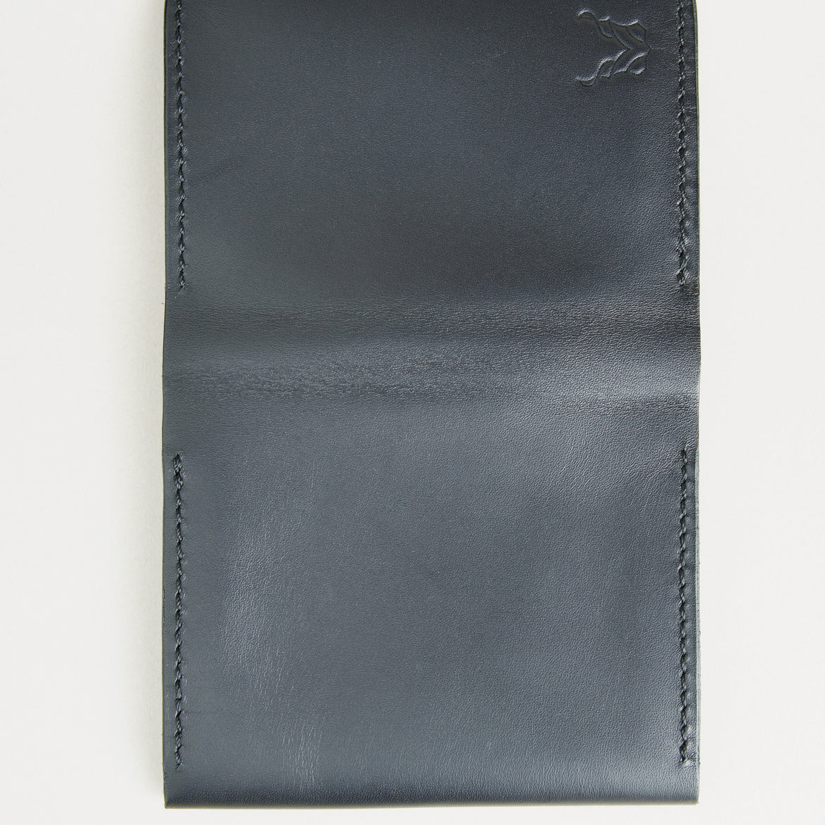 Outside view of midnight black full-grain leather flap fold wallet featuring handmade stitching and embossed logo. Markore Khaas Andaz.