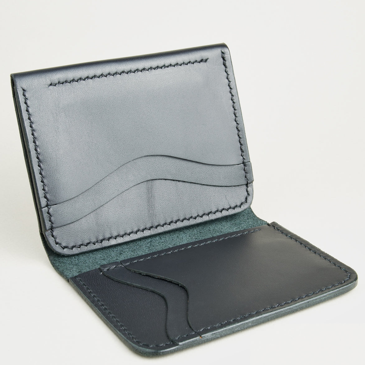 Side view of midnight black full-grain leather flap fold wallet featuring a flap closure, vertical and horizontal card slots and handmade stitching. Markore Khaas Andaz.