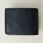 Back view of midnight black full-grain leather wallet featuring a seamless bottom edge and handmade stitching. Markore Assam Silk.