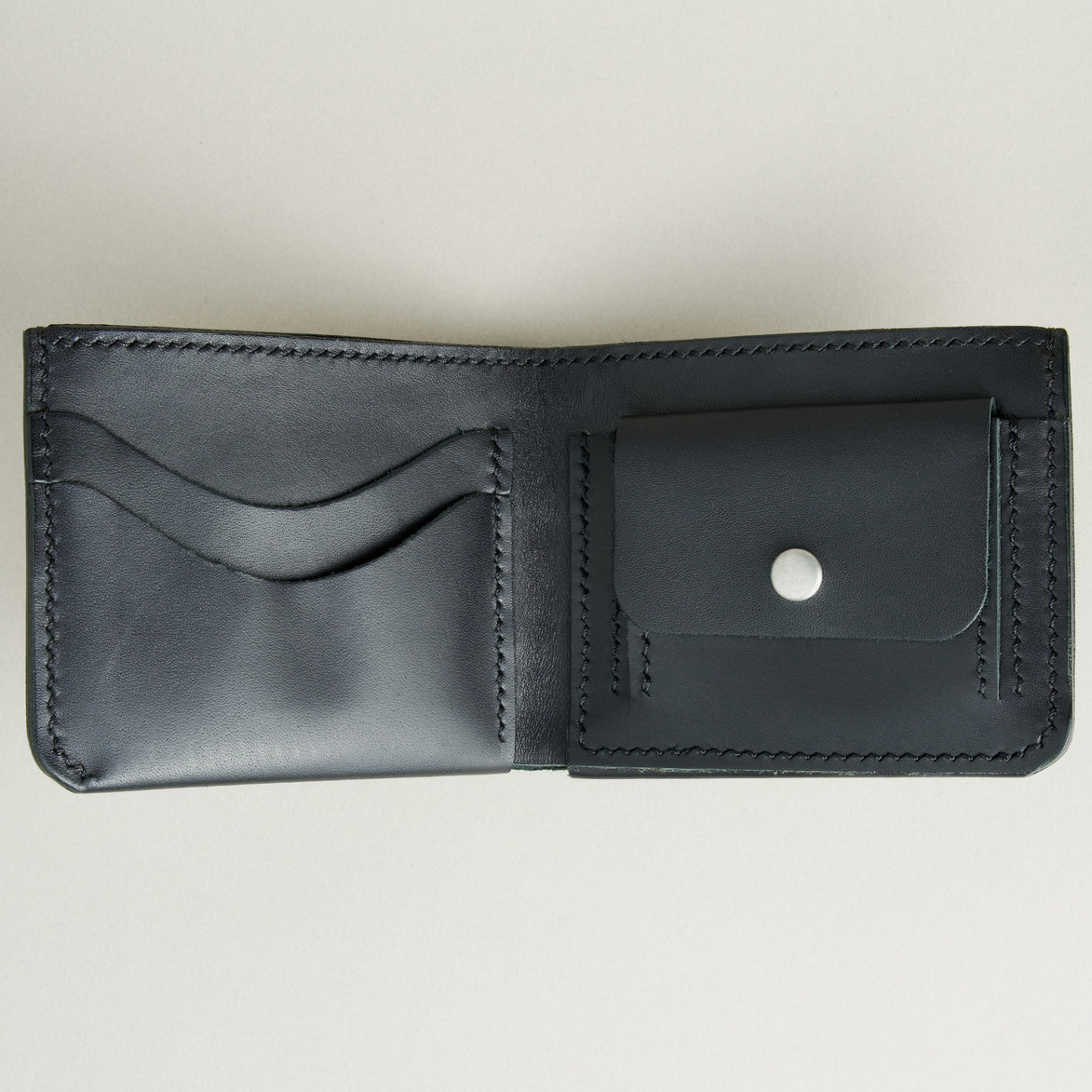 Inside view of midnight black full-grain leather wallet featuring a seamless bottom edge, card slots, coin pocket with stainless steel press stud and  handmade stitching. Markore Assam Silk.