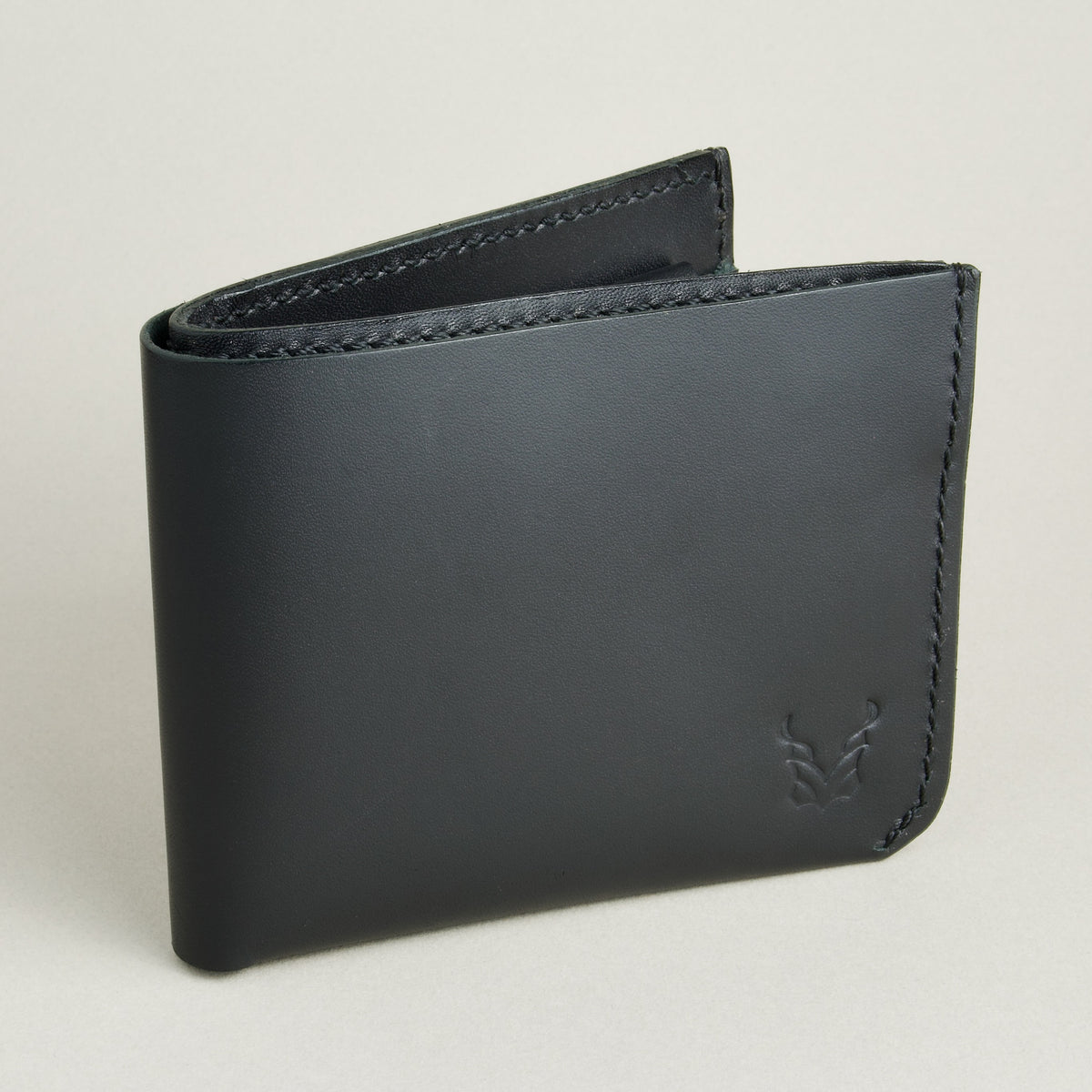 Side view of midnight black full-grain leather wallet featuring a seamless bottom edge, handmade stitching and embossed logo. Markore Assam Silk.