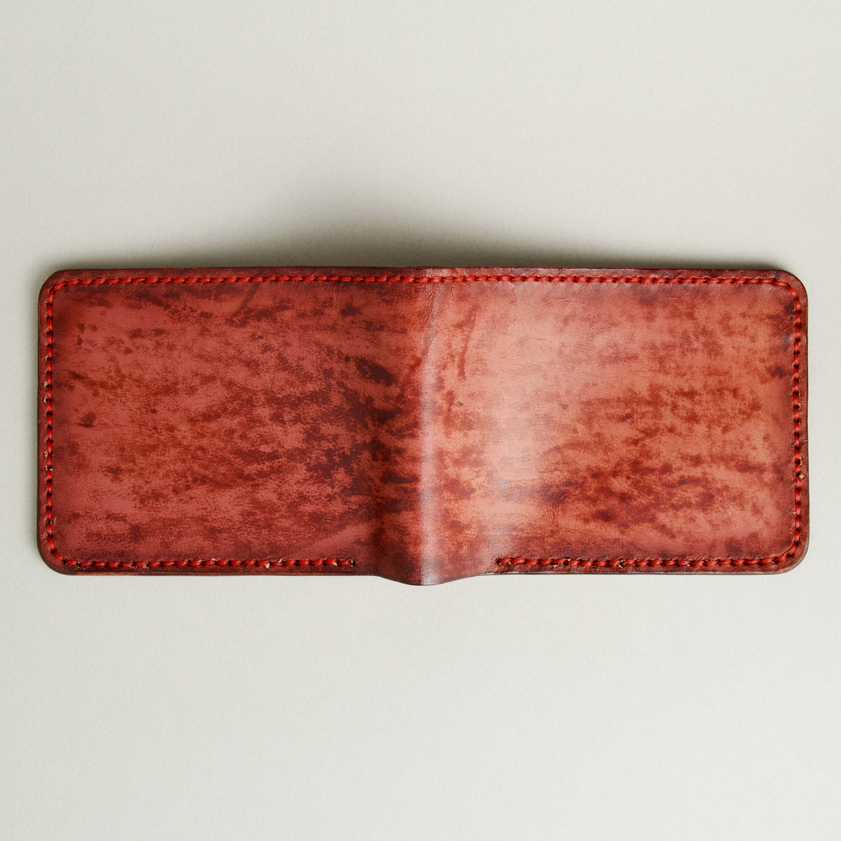 Unfolded outside view of hand-painted full-grain leather bifold wallet in red, featuring handmade stitching. Markore Canvas Flame.