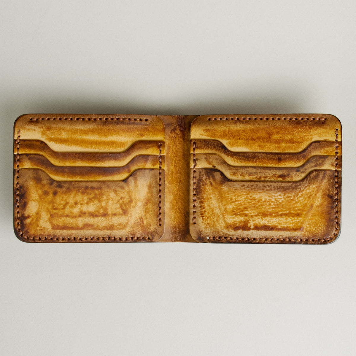 Inside view of hand-painted full-grain leather bifold wallet in amber and brown, featuring card slots and handmade stitching. Markore Canvas Flame.