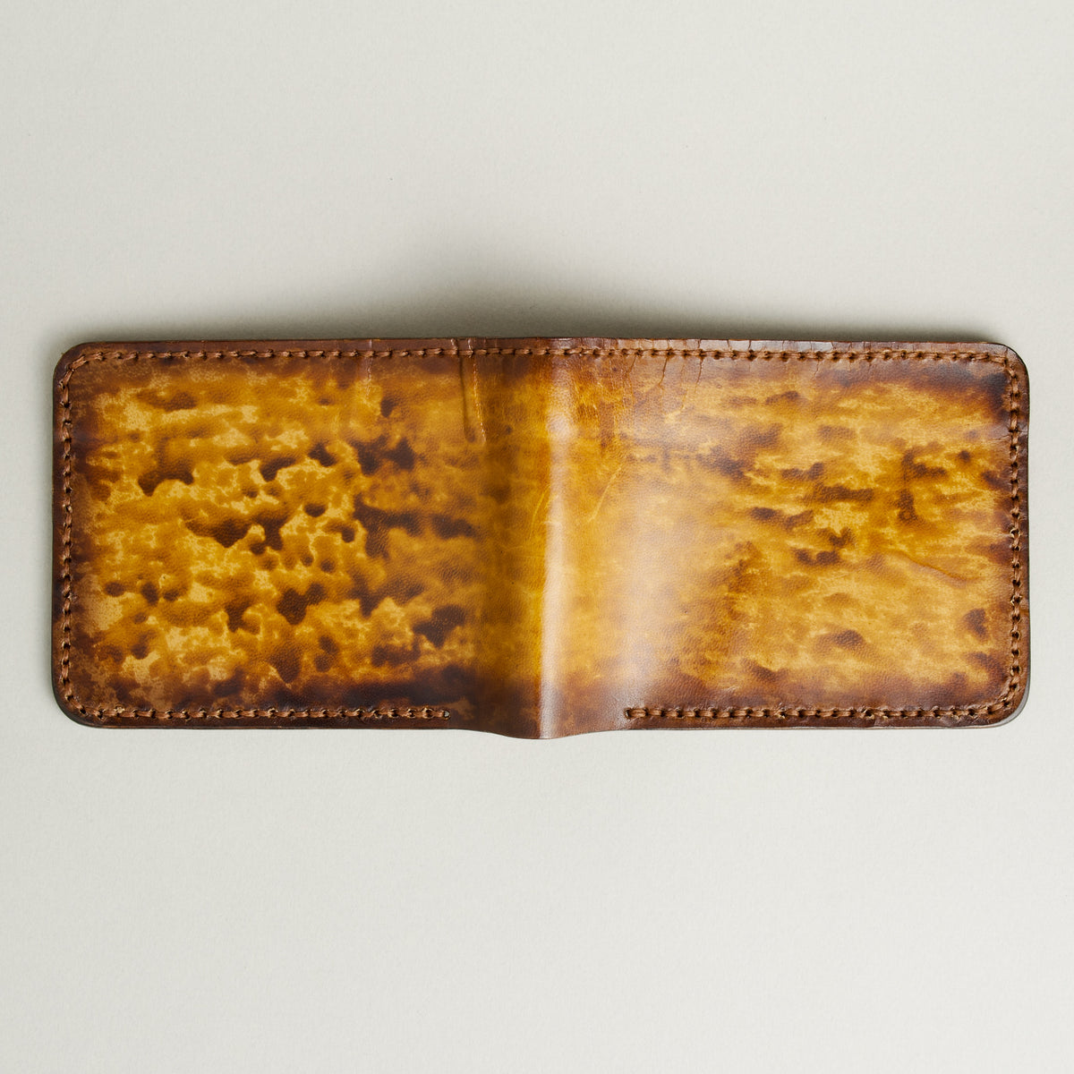 Unfolded outside view of hand-painted full-grain leather bifold wallet in amber and brown, featuring handmade stitching. Markore Canvas Flame.