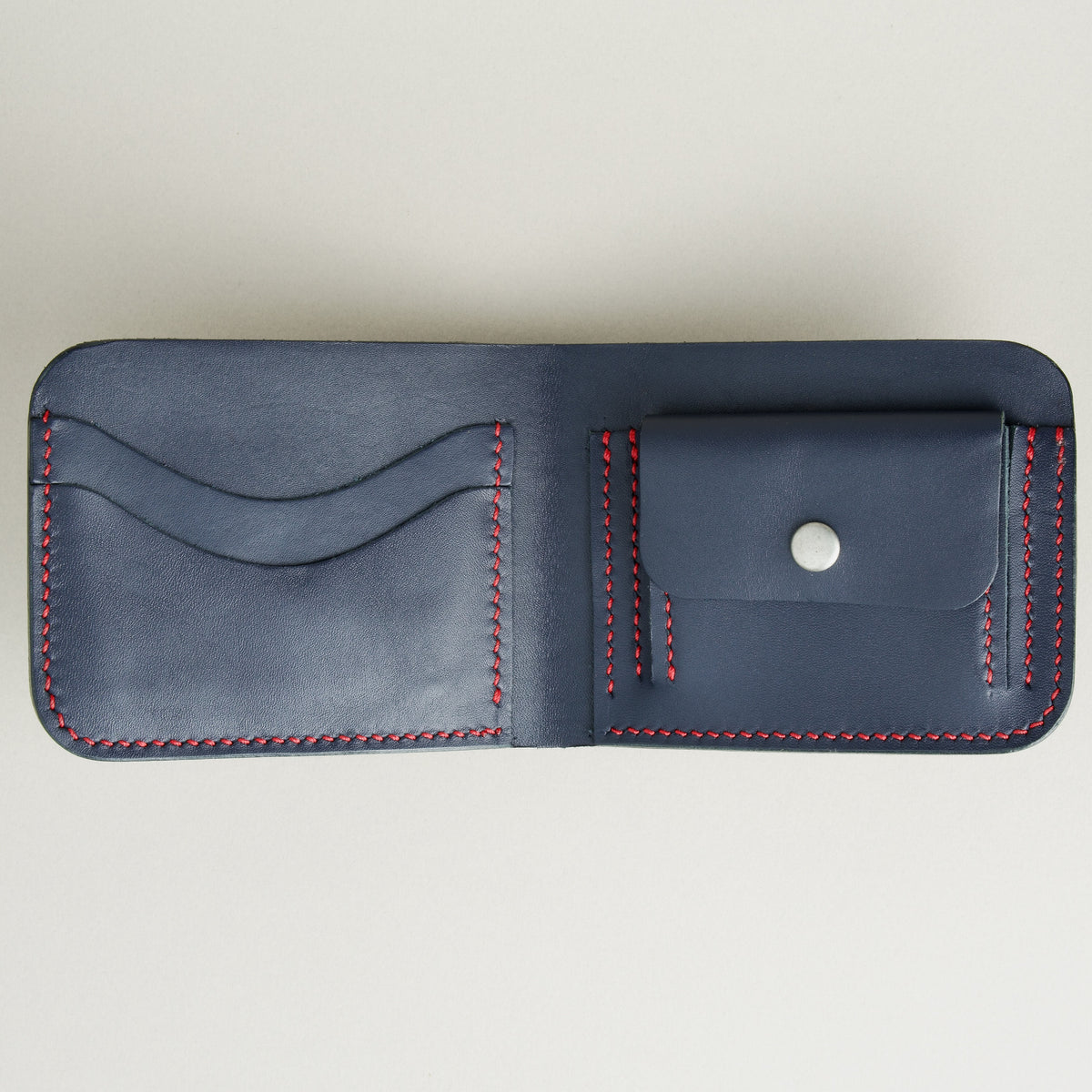 Inside view of full-grain leather bifold wallet with coin pocket and card slots, and hand-stitched red thread in Dark Blue Markore Hunza Arc.