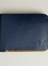 Front view of dark blue full-grain leather bifold wallet featuring handmade amber cross-stitched detailing on the edges and embossed logo. Markore Hunza Edge.