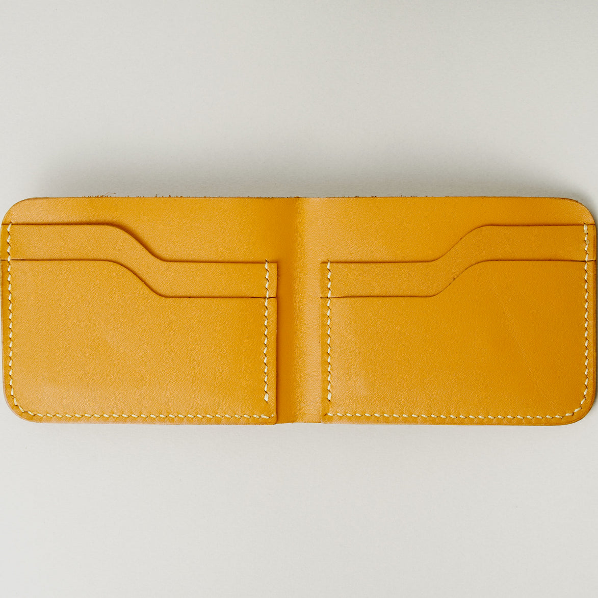 Inside view of full grain leather bifold wallet in amber, featuring ivory handmade stitching and card slots. Markore Hunza Fold.