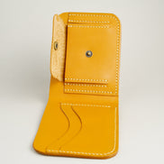 Inside view of full grain leather bifold wallet in amber, featuring ivory handmade stitching, a coin pocket with brass press button and card slots. Markore Hunza Fold.