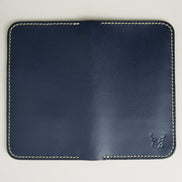 Unfolded back view of vertical full-grain leather bifold wallet in Dark Blue, featuring handmade stitching in ivory and embossed logo. Markore Karakoram II.