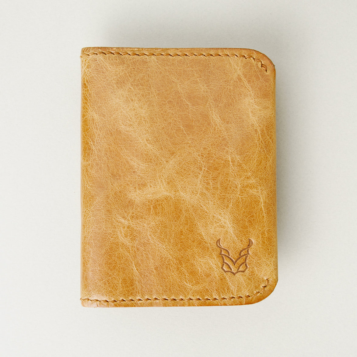 Front view of leather bifold wallet in natural, featuring handmade stitching and embossed logo. Markore Natural.