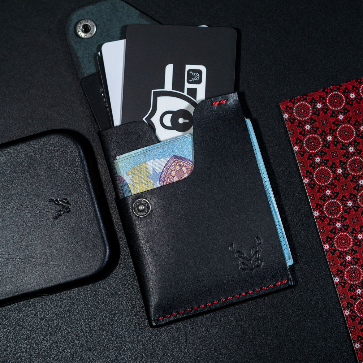markore niva heritage in midnight black with red stitching and markore shell frame iphone 17 pro leather case sitting on a black surface