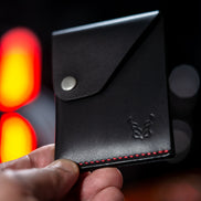 markore niva heritage ultra compact card sleeve in midnight black with red stitching held in hand 