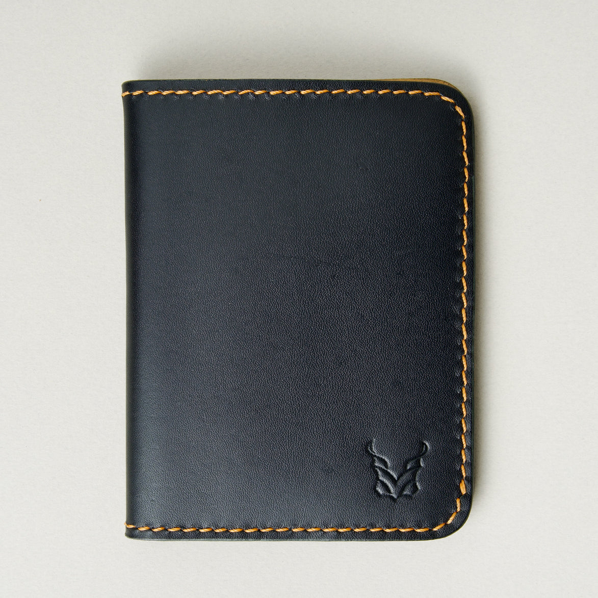 Front view of midnight black full-grain leather wallet featuring amber handmade stitching and embossed logo. Markore Ravi Fold.