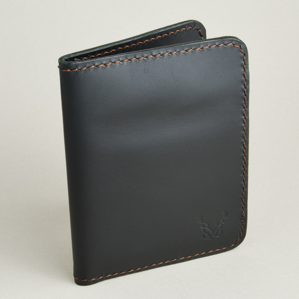 Side view of midnight black full-grain leather wallet featuring espresso brown handmade stitching and embossed logo. Markore Ravi Fold.