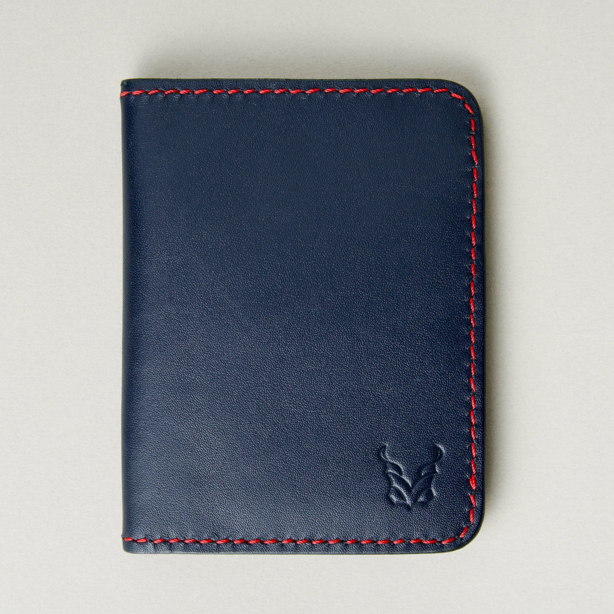 Front view of dark blue full-grain leather wallet featuring red handmade stitching and embossed logo. Markore Ravi Fold.