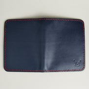 Outside view of dark blue full-grain leather vertical wallet featuring red handmade stitching and embossed logo. Markore Ravi Fold.