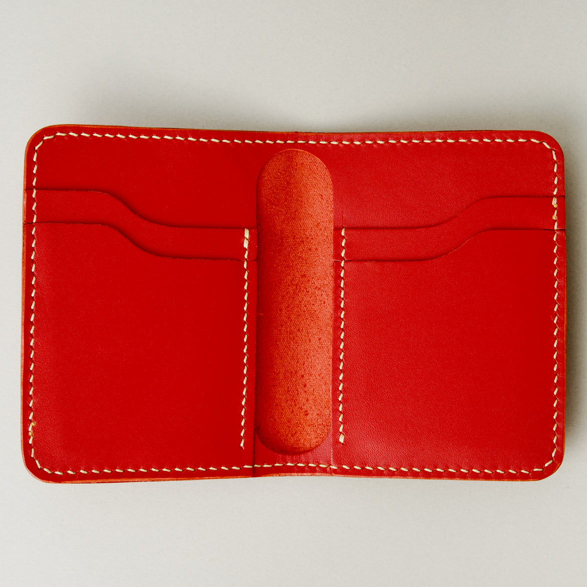 Inside view of red full-grain leather wallet featuring card slots and ivory handmade stitching. Markore Ravi Fold.