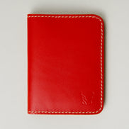 Front view of red full-grain leather wallet featuring ivory handmade stitching and embossed logo. Markore Ravi Fold.