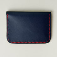 Back view of dark blue full-grain leather wallet featuring red handmade stitching. Markore Ravi Slip.