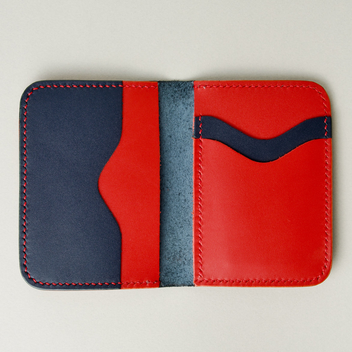 Inside view of dark blue full-grain leather wallet featuring red and dark blue card slots and red handmade stitching. Markore Ravi Slip.