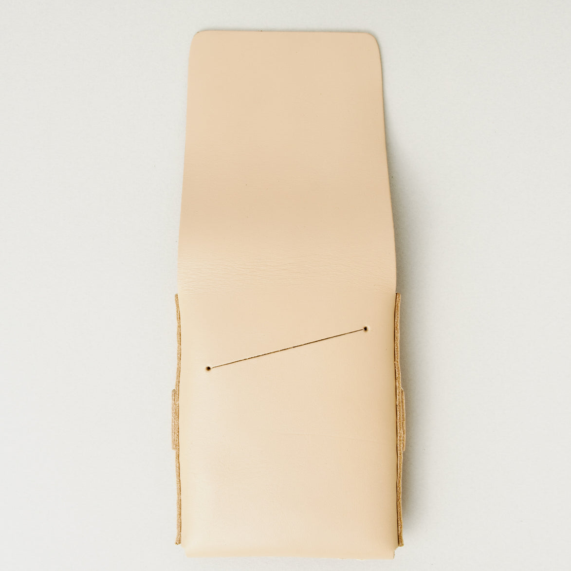 Back view of natural full-grain leather flap wallet with open flap featuring a card slot and handmade stitching. Markore Sutlej Vault.