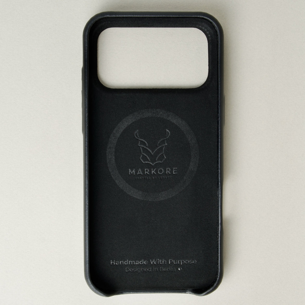 Inside view of midnight black leather iphone 17 pro case with full cutout showing velvet lining and brand logo. Markore Shell Frame.